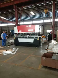 Osm OG-100II Down-Acting CNC Hydraulic Press Brake in Customer Facility: Skilled Operator Performing Precision Metal Sheet Bending with ±0.01mm Tolerance, Equipped with Intelligent CNC Control System and Hydraulic Synchronization Technology, Demonstrating