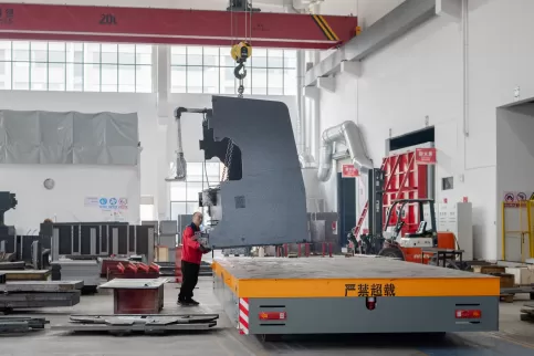 Real-life images of the precision manufacturing of the Osm bending machine body, showcasing the CNC machining of high-rigidity welded structural components. The image focuses on workers hoisting the welded rack, presenting a panoramic view of the full-pro