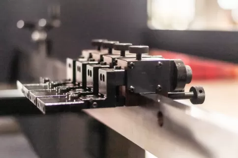 Close-up of the semi-automatic back gauge system on the OSM press brake, featuring a high-rigidity steel scale system equipped with manually adjustable positioning stops for millimeter-level precision positioning and quick assembly/disassembly.  The singl