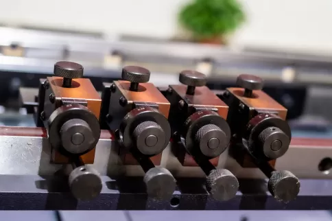 Close-up of the front of the OSM press brake's semi-automatic rear stop system, showcasing the core of the high-rigidity steel scale system. Equipped with precision manually adjustable positioning blocks, it achieves millimeter-level precise positioning a