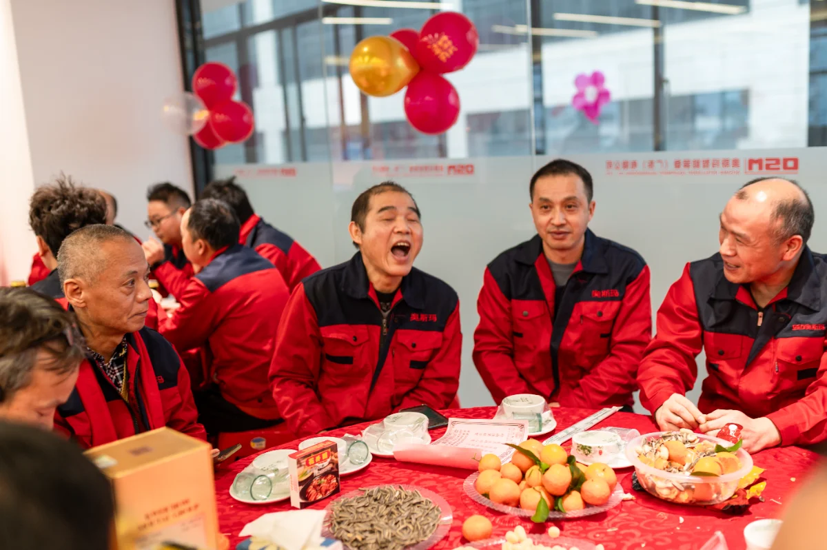 OSM employees in red uniforms celebrate at the 2026 Annual Company Meeting. The image captures a joyful team gathering with festive decorations, snacks, and a warm, unified atmosphere reflecting company culture.
