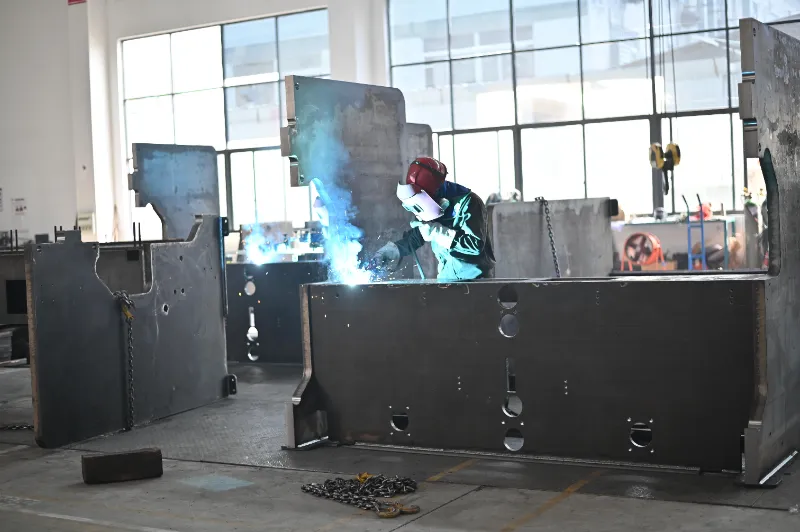 OSM press brake manufacturing process photo showing worker welding the machine body, highlighting advanced welding technology and strict quality control.